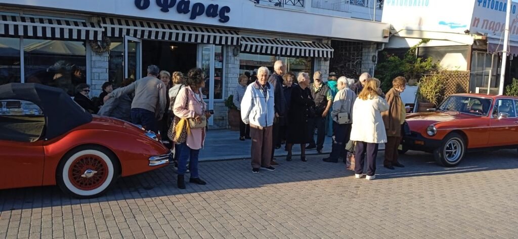 Η παρέα της εκδρομής του Συλλόγου έξω από ταβέρνα στον Μαραθώνα, με κλασικά αυτοκίνητα σταθμευμένα δίπλα.